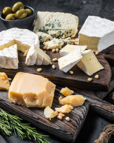Delicious Cheese board.  Assortment of cheese, camembert, brie, Gorgonzola, parmesan, olives, nuts and herbs. Black background. Top view.